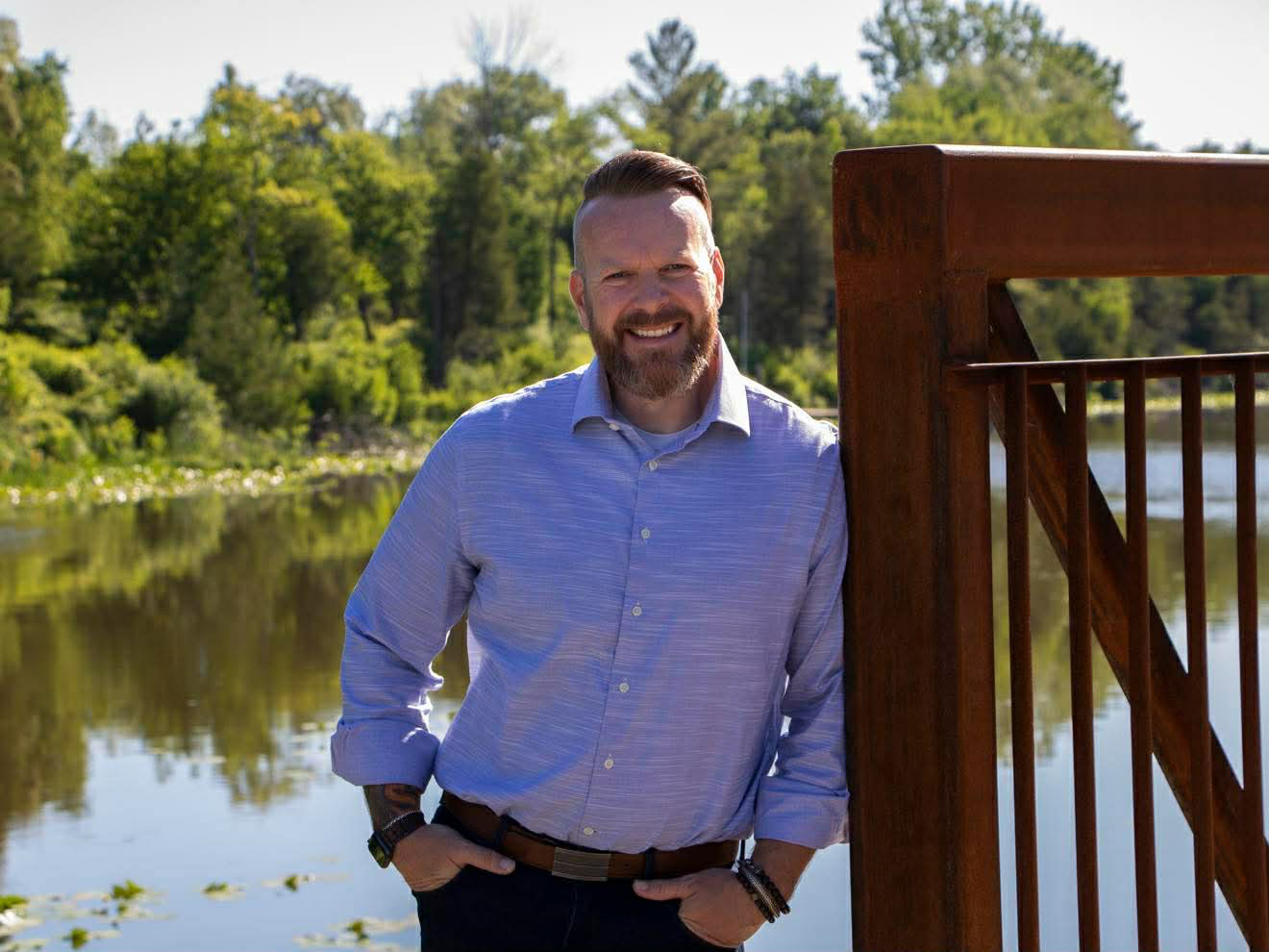 Rhyus Reeves standing beside a wooden railing by the water